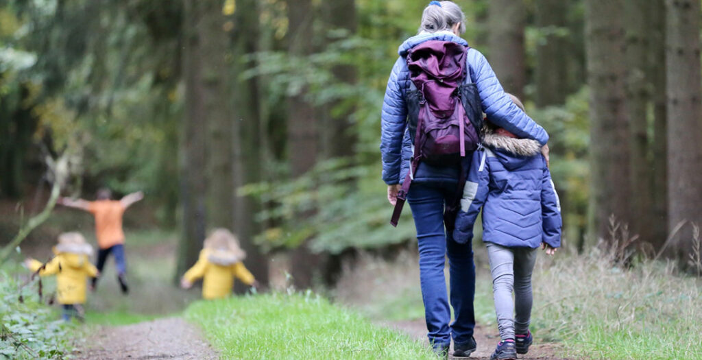 Scolaresca a passeggio in un bosco con l'insegnante - Foto di Juliane Liebermann su Unsplash